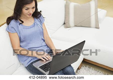 Stock Photography - Woman using laptop on sofa. Fotosearch