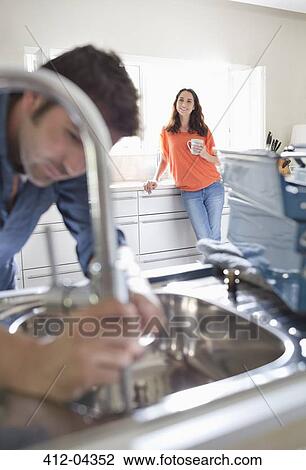 Woman watching plumber work on kitchen sink View Large Photo Image Stock Image - Woman watching plumber work on kitchen sink. Fotosearch