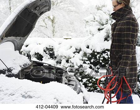 Stock Photo - Woman working on broken down car in snow. Fotosearch
