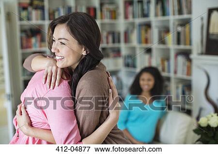 Women hugging in living room View Large Photo Image Stock Photo - Women hugging in living room. Fotosearch