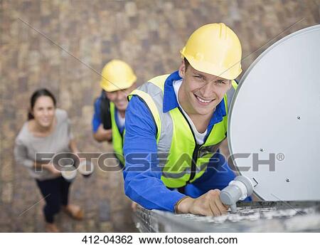 Workers installing satellite dish on roof View Large Photo Image Stock Image - Workers installing satellite dish on roof. Fotosearch