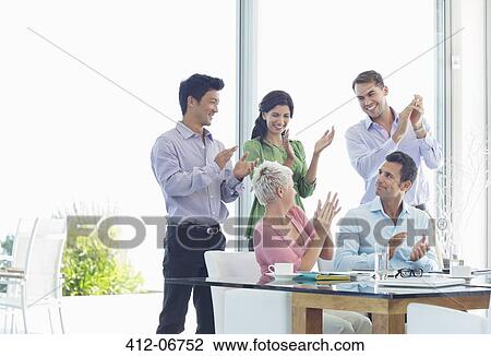 Stock Image - Business people cheering in meeting. Fotosearch