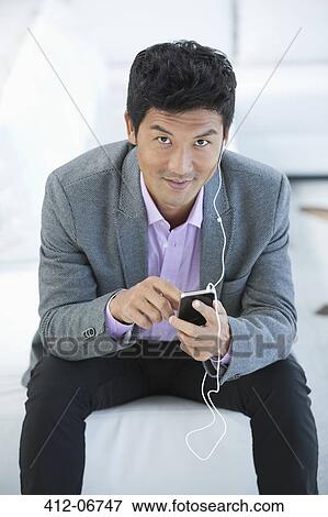 Businessman listening to headphones on sofa View Large Photo Image Stock Photo - Businessman listening to headphones on sofa. Fotosearch