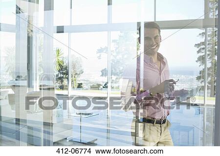 Businessman smiling at office window View Large Photo Image Picture - Businessman smiling at office window. Fotosearch