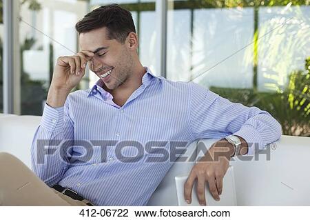 Stock Image - Businessman smiling on sofa. Fotosearch
