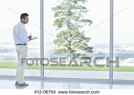 Picture - Businessman using tablet computer at office window. Fotosearch