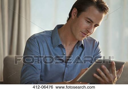 Stock Photograph - Businessman using tablet computer on sofa. Fotosearch