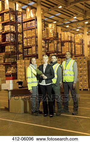 Stock Photograph - Businesswoman and workers smiling in warehouse. Fotosearch
