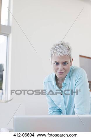 Businesswoman standing at desk in office View Large Photo Image Picture - Businesswoman standing at desk in office. Fotosearch