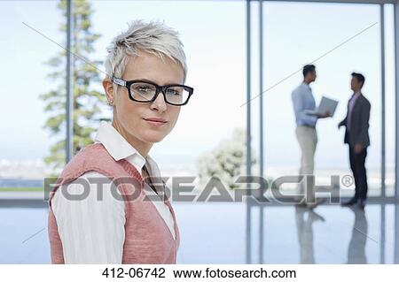 Stock Image - Businesswoman standing in office. Fotosearch