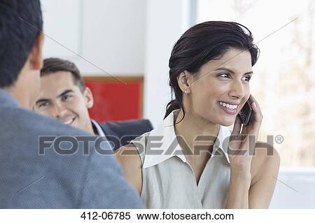 Stock Photography - Businesswoman talking on cell phone in office. Fotosearch