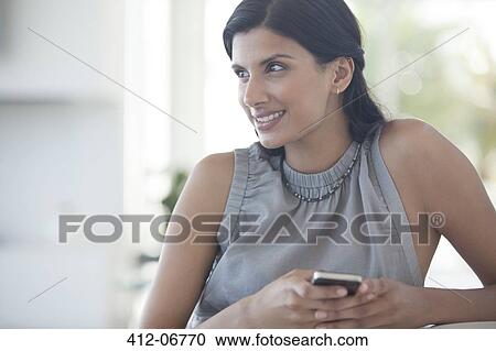 Stock Image - Businesswoman using cell phone in office. Fotosearch