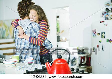 Stock Image - Couple hugging in kitchen. Fotosearch