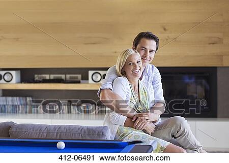 Couple hugging on sofa in living room View Large Photo Image Stock Image - Couple hugging on sofa in living room. Fotosearch