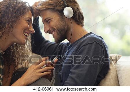 Couple listening to headphones on sofa View Large Photo Image Stock Image - Couple listening to headphones on sofa. Fotosearch