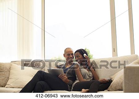 Stock Image - Couple relaxing together on sofa. Fotosearch