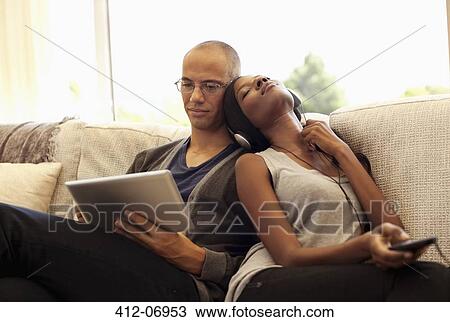 Stock Image - Couple relaxing together on sofa. Fotosearch