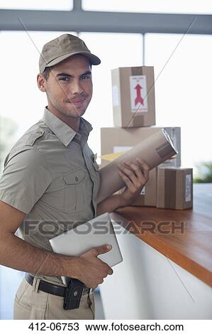 Delivery boy with packages in office View Large Photo Image Stock Image - Delivery boy with packages in office. Fotosearch
