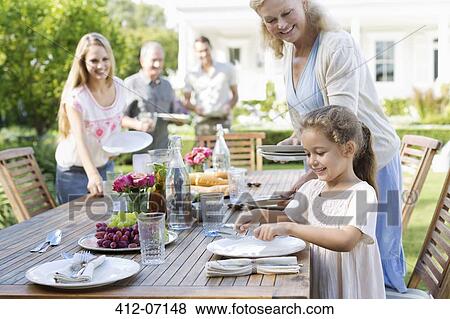 Stock Photo - Family setting table outdoors. Fotosearch