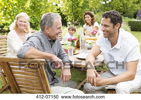 Family sitting at table outdoors View Large Photo Image Stock Image - Family sitting at table outdoors. Fotosearch