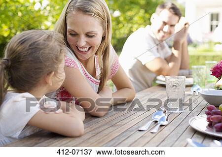 Family sitting at table outdoors View Large Photo Image Stock Photo - Family sitting at table outdoors. Fotosearch