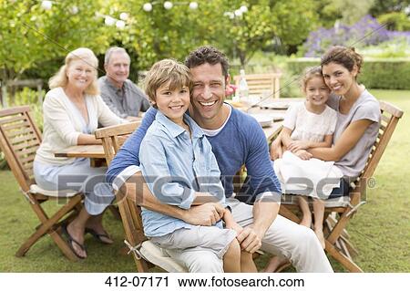Family smiling at table outdoors View Large Photo Image Stock Image - Family smiling at table outdoors. Fotosearch