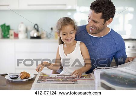 Father and daughter reading newspaper at breakfast View Large Photo Image Picture - Father and daughter reading newspaper at breakfast. Fotosearch