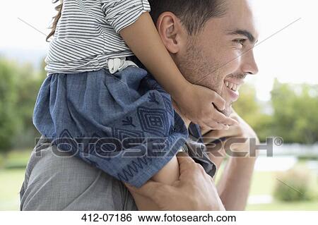Stock Photograph - Father carrying daughter on shoulders outdoors. Fotosearch