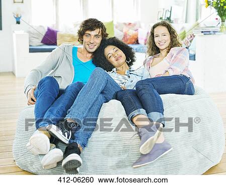 Stock Image - Friends relaxing together in beanbag chair. Fotosearch