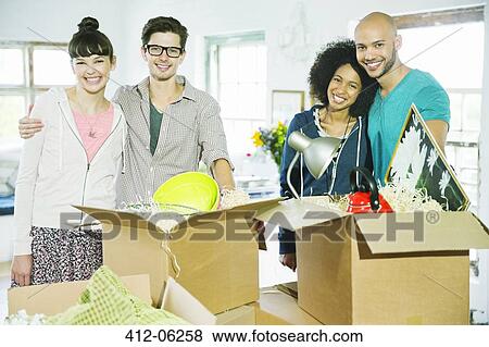 Stock Photo - Friends unpacking boxes in new home. Fotosearch