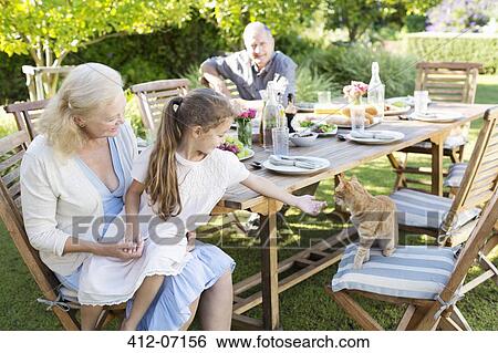 Girl asking to pet cat at table outdoors View Large Photo Image Stock Photograph - Girl asking to pet cat at table outdoors. Fotosearch
