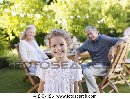 Girl smiling in backyard with grandparents View Large Photo Image Stock Photography - Girl smiling in backyard with grandparents. Fotosearch