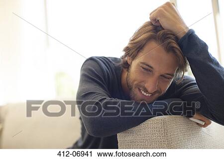 Stock Image - Man leaning on arm of sofa. Fotosearch