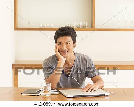 Man listening to headphones at table View Large Photo Image Stock Photo - Man listening to headphones at table. Fotosearch
