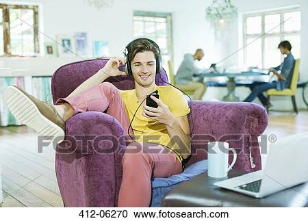 Man listening to headphones in armchair View Large Photo Image Stock Image - Man listening to headphones in armchair. Fotosearch