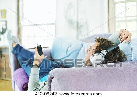 Man listening to headphones on sofa View Large Photo Image Stock Image - Man listening to headphones on sofa. Fotosearch