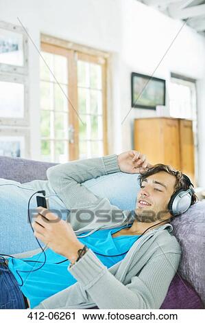 Man listening to headphones on sofa View Large Photo Image Stock Image - Man listening to headphones on sofa. Fotosearch