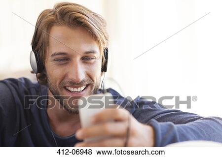 Man listening to headphones on sofa View Large Photo Image Stock Photo - Man listening to headphones on sofa. Fotosearch