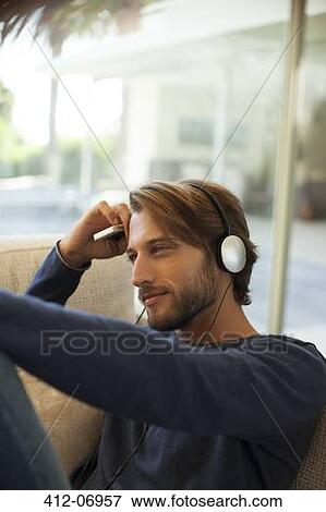 Man listening to headphones on sofa View Large Photo Image Stock Photo - Man listening to headphones on sofa. Fotosearch
