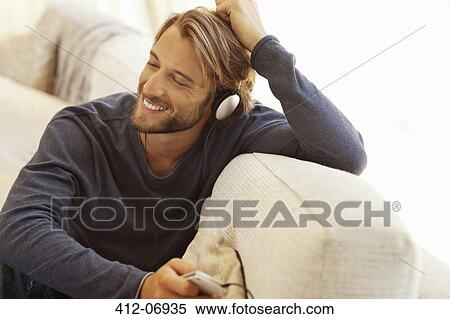 Man listening to headphones on sofa View Large Photo Image Stock Photography - Man listening to headphones on sofa. Fotosearch