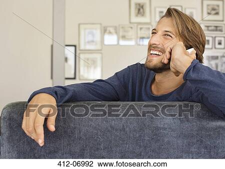 Man talking on cell phone on sofa View Large Photo Image Stock Image - Man talking on cell phone on sofa. Fotosearch