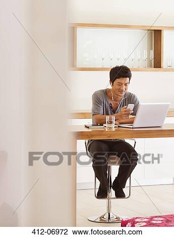 Man using cell phone and laptop at table View Large Photo Image Stock Image - Man using cell phone and laptop at table. Fotosearch