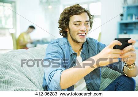 Man using cell phone in beanbag chair View Large Photo Image Stock Image - Man using cell phone in beanbag chair. Fotosearch