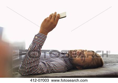Stock Image - Man using cell phone on bench. Fotosearch