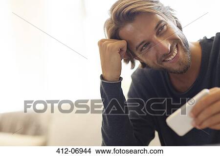 Man using cell phone on sofa View Large Photo Image Picture - Man using cell phone on sofa. Fotosearch