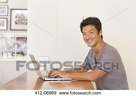 Stock Photo - Man using laptop at table. Fotosearch