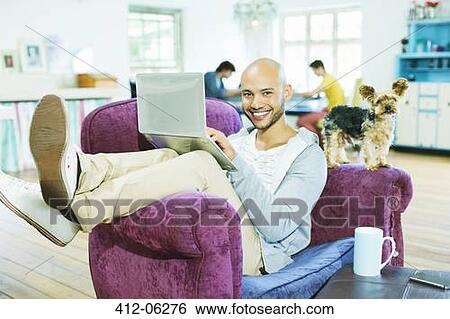 Man using laptop in armchair View Large Photo Image Stock Photograph - Man using laptop in armchair. Fotosearch
