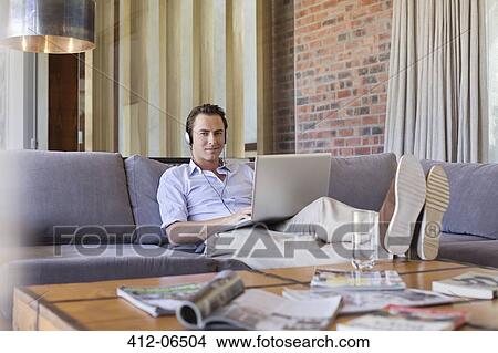 Man using laptop on sofa View Large Photo Image Picture - Man using laptop on sofa. Fotosearch