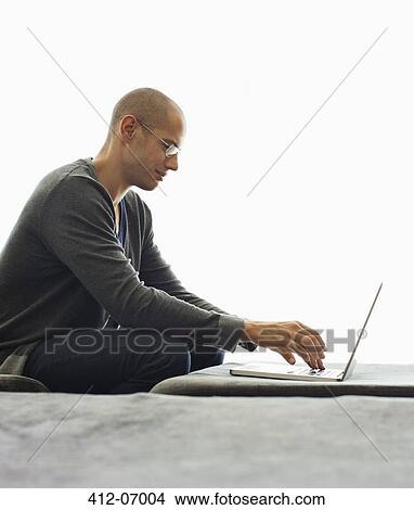 Picture - Man using tablet computer in living room. Fotosearch