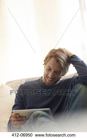 Man using tablet computer on sofa View Large Photo Image Stock Image - Man using tablet computer on sofa. Fotosearch